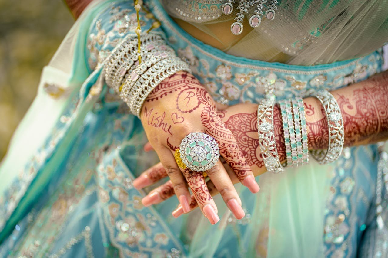 Close-up of bridal hands adorned with intricate mehndi and jewelry, showcasing vibrant cultural elegance.