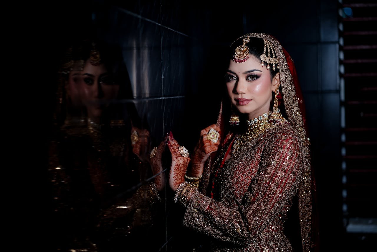 Stunning South Asian bride with exquisite jewelry and intricate attire posing elegantly indoors.